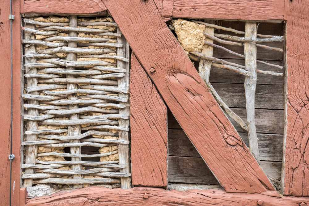 Nahaufnahme einer baufälligen Fachwerkwand aus Holz und Lehm.